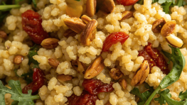 Hirse mit getrockneten Tomaten, Ruccula und Pinienkernen vermischt.